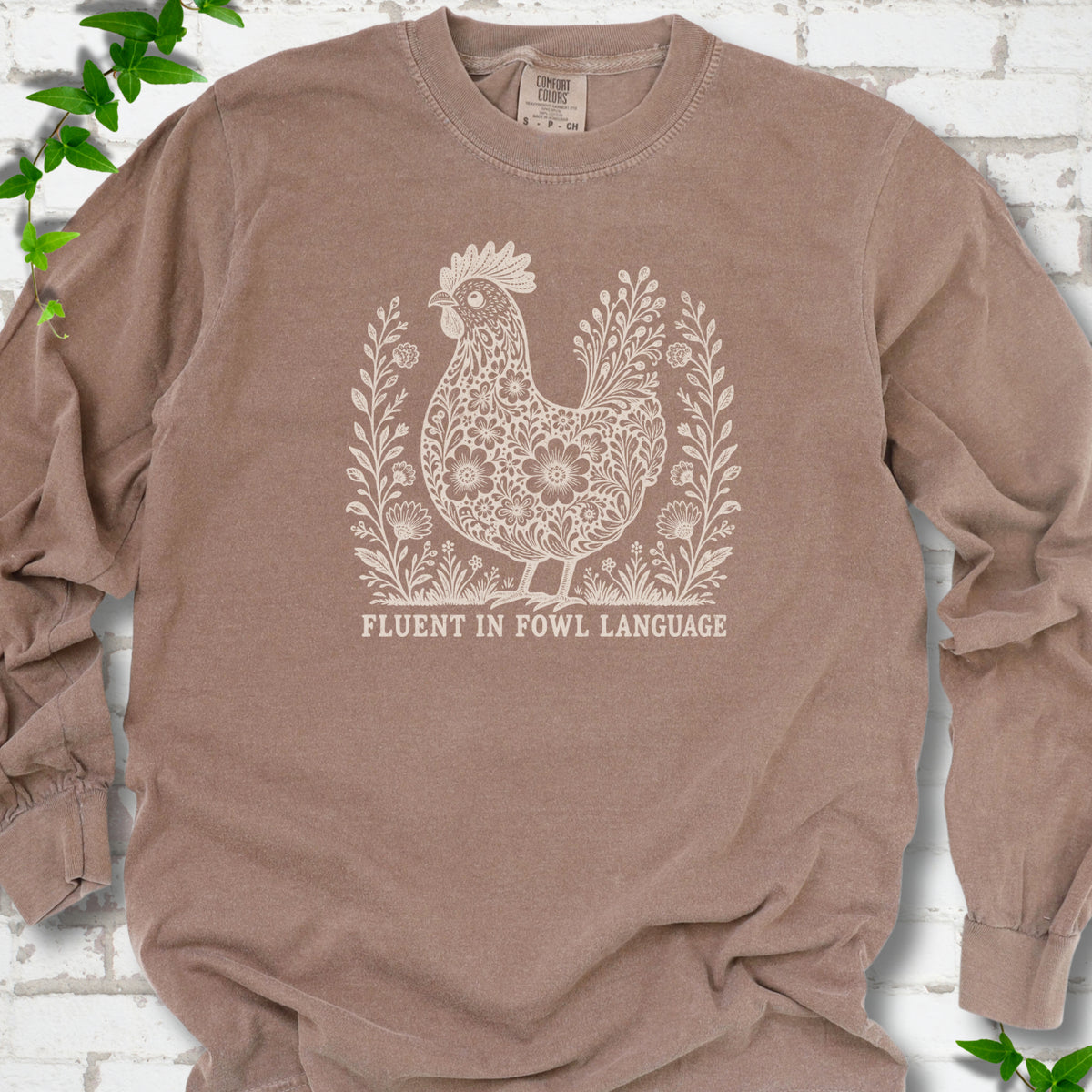 Espresso Comfort Colors® long sleeve T-shirt with cream floral hen and Fluent in Fowl Language text