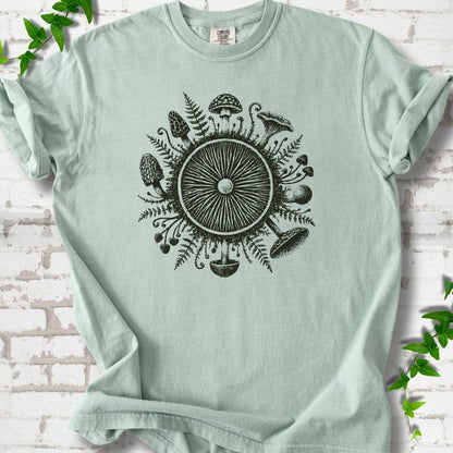 Bay green short-sleeve tee with a mushroom gill circle ringed by ferns, morels and mushrooms in dark green ink.