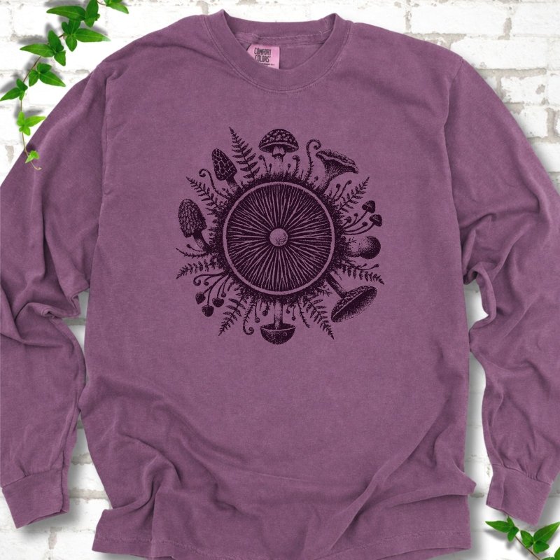 Berry purple long-sleeve tee with a mushroom gill circle ringed by ferns, morels and mushrooms in dark plum ink.