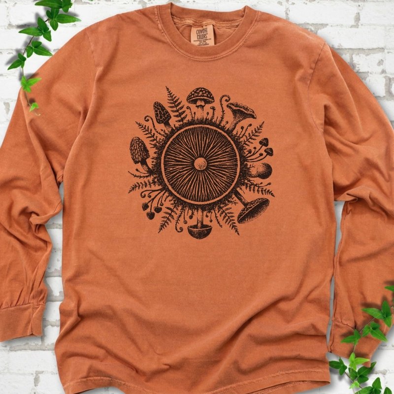Yam orange long-sleeve tee with a mushroom gill circle ringed by ferns, morels and mushrooms in black ink.
