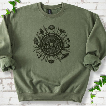 Military green crewneck sweatshirt with a mushroom gill circle ringed by ferns, morels and mushrooms in dark green ink.