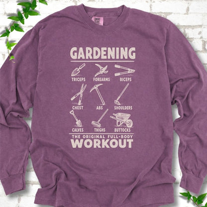 Berry Comfort Colors® long sleeve T-shirt flat lay featuring a distressed Gardening full-body workout design with labelled garden tools and wheelbarrow.