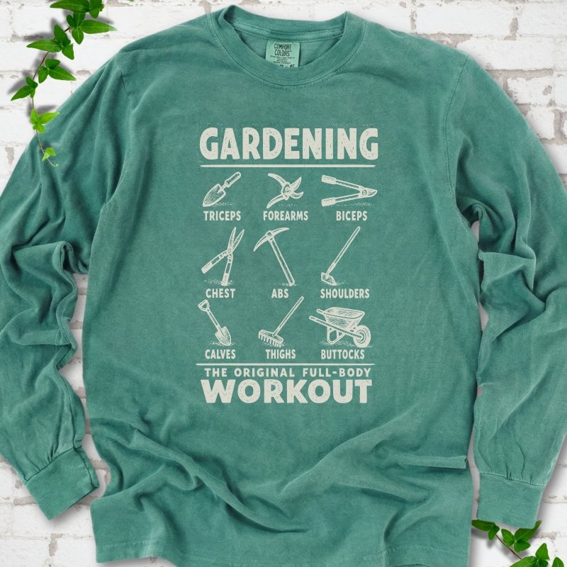 Light Green Comfort Colors® long sleeve T-shirt flat lay featuring a distressed Gardening full-body workout design with labelled garden tools and wheelbarrow.