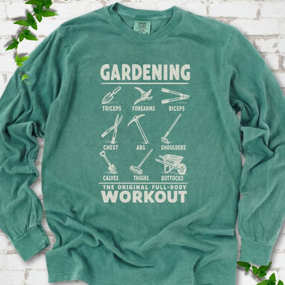 Light Green Comfort Colors® long sleeve T-shirt flat lay featuring a distressed Gardening full-body workout design with labelled garden tools and wheelbarrow.