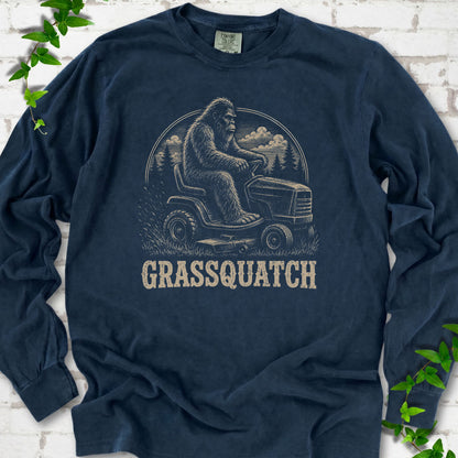 Midnight Comfort Colors® long sleeve T-shirt front mockup featuring Bigfoot riding a lawn mower above the word Grassquatch.