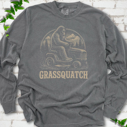 Pepper Comfort Colors® long sleeve T-shirt front mockup featuring Bigfoot riding a lawn mower above the word Grassquatch.