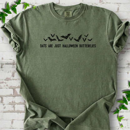 Moss Comfort Colors® T-shirt flat lay with black flying bats and “Bats Are Just Halloween Butterflies” lettering.