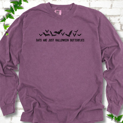 Berry Comfort Colors® long sleeve tee flat lay with black flying bats and “Bats Are Just Halloween Butterflies” lettering.