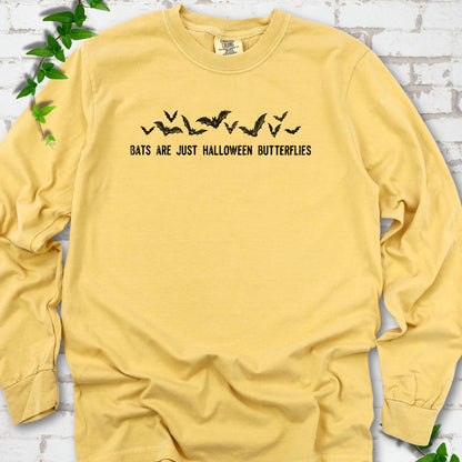 Mustard Comfort Colors® long sleeve tee flat lay with black flying bats and “Bats Are Just Halloween Butterflies” lettering.