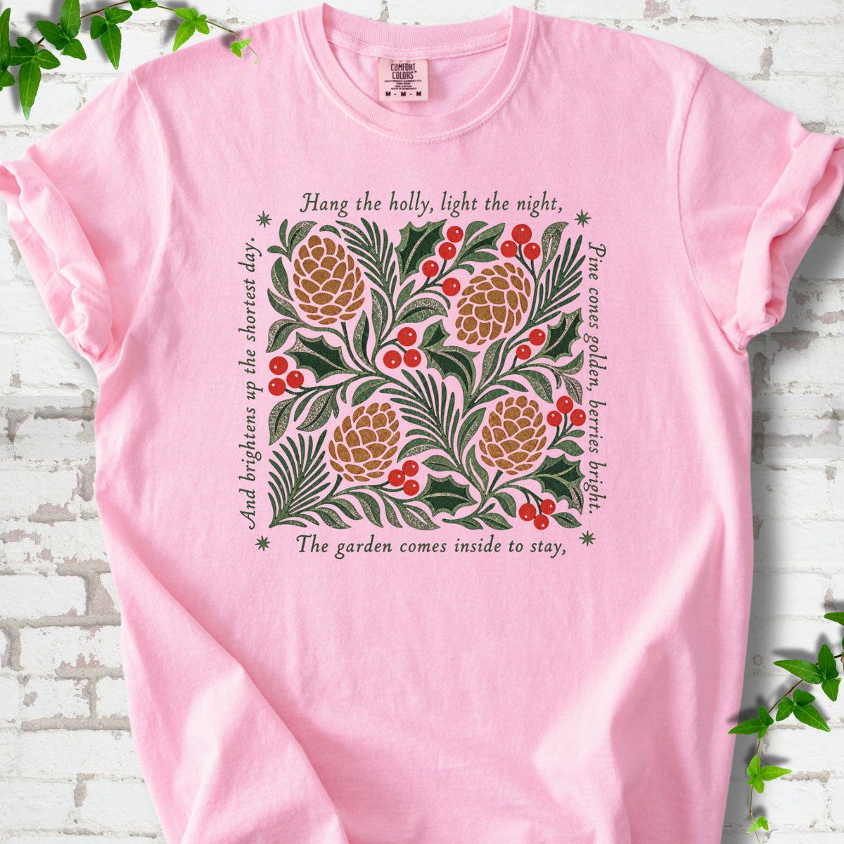 Blossom Comfort Colors® T-shirt shown flat with green holly, red berries, pine cones and the "Hang the Holly" seasonal verse