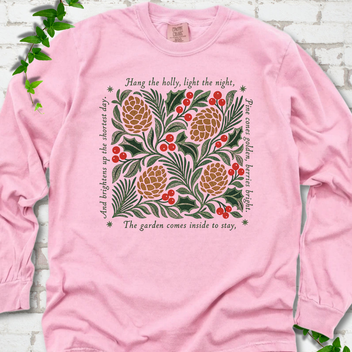 Blossom Comfort Colors® long sleeve T-shirt shown flat with green holly, red berries, pine cones and the "Hang the Holly" seasonal verse