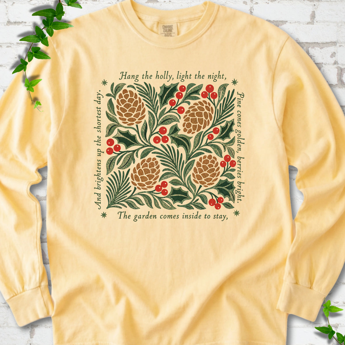 Butter Comfort Colors® long sleeve T-shirt shown flat with green holly, red berries, pine cones and the "Hang the Holly" seasonal verse