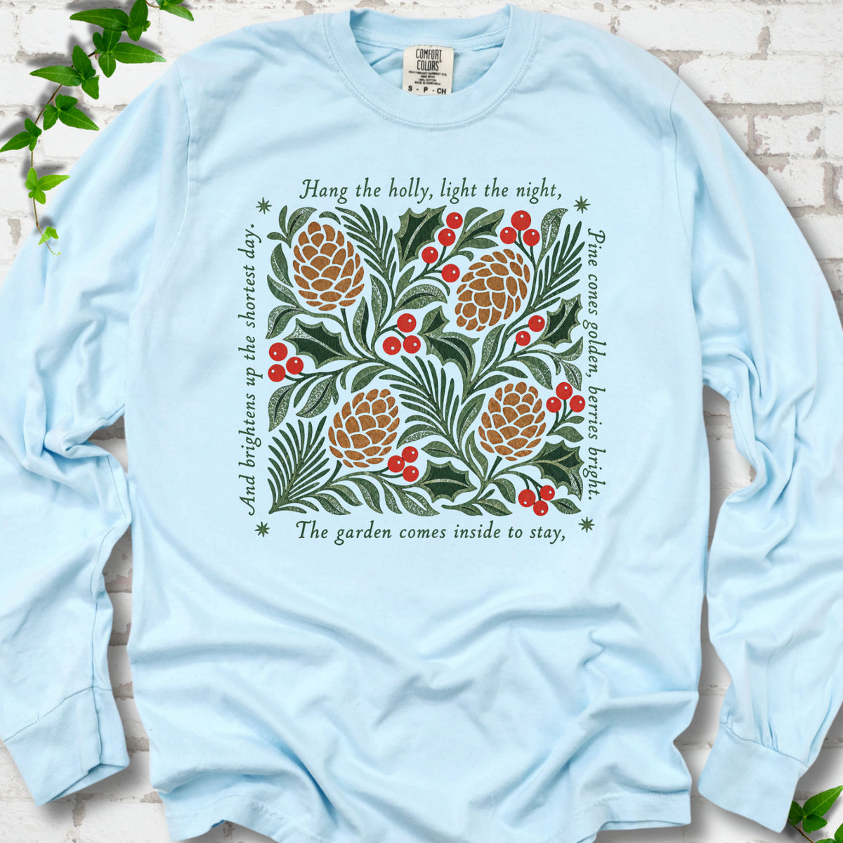 Chambray Comfort Colors® long sleeve T-shirt shown flat with green holly, red berries, pine cones and the "Hang the Holly" seasonal verse