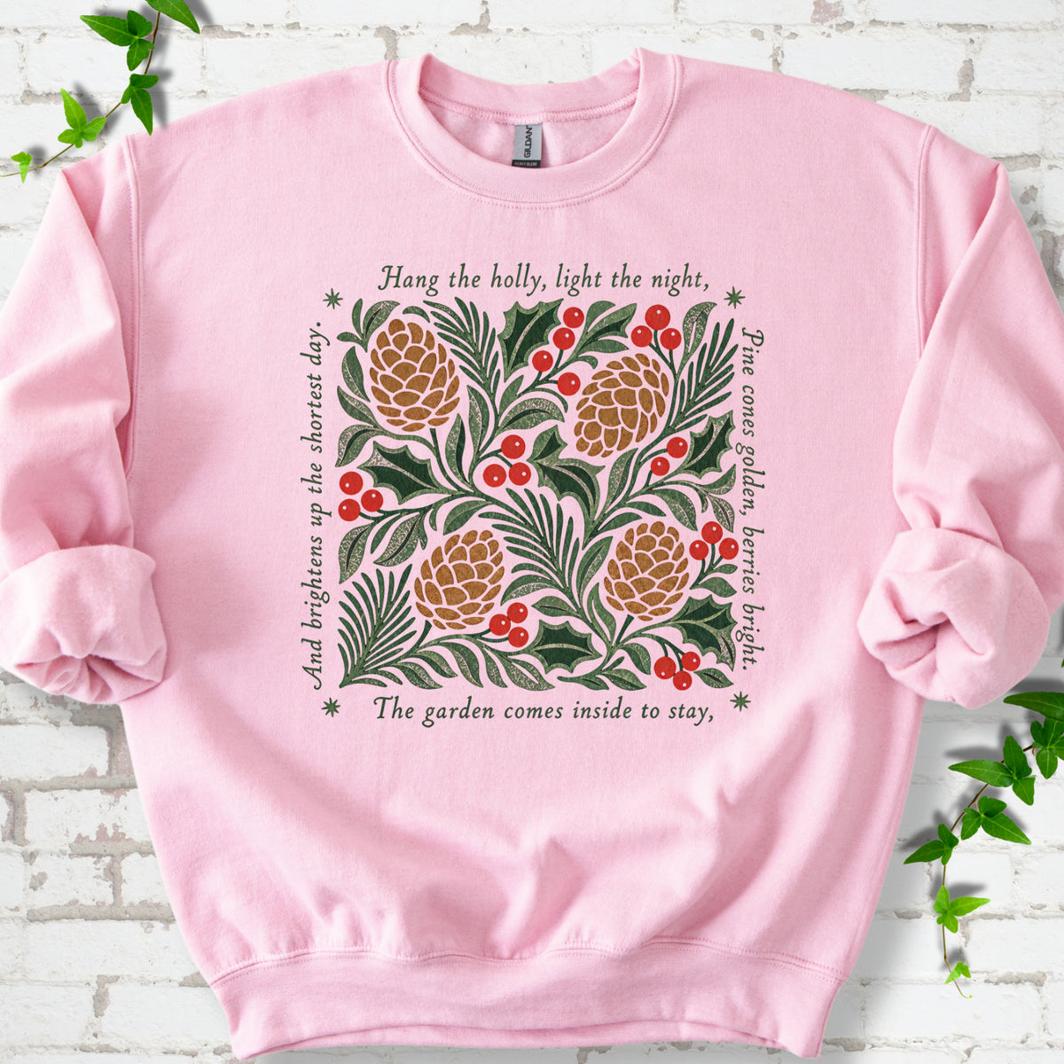 Light Pink classic sweatshirt shown flat with green holly, red berries, pine cones and the "Hang the Holly" seasonal verse