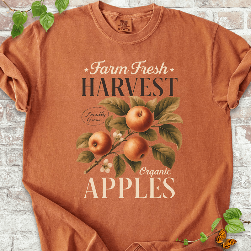 Harvest Apples T-shirt on Comfort Colors™ Yam – displays a nostalgic apple-picking graphic with three ripe apples, blossoming flowers, and rustic harvest typography