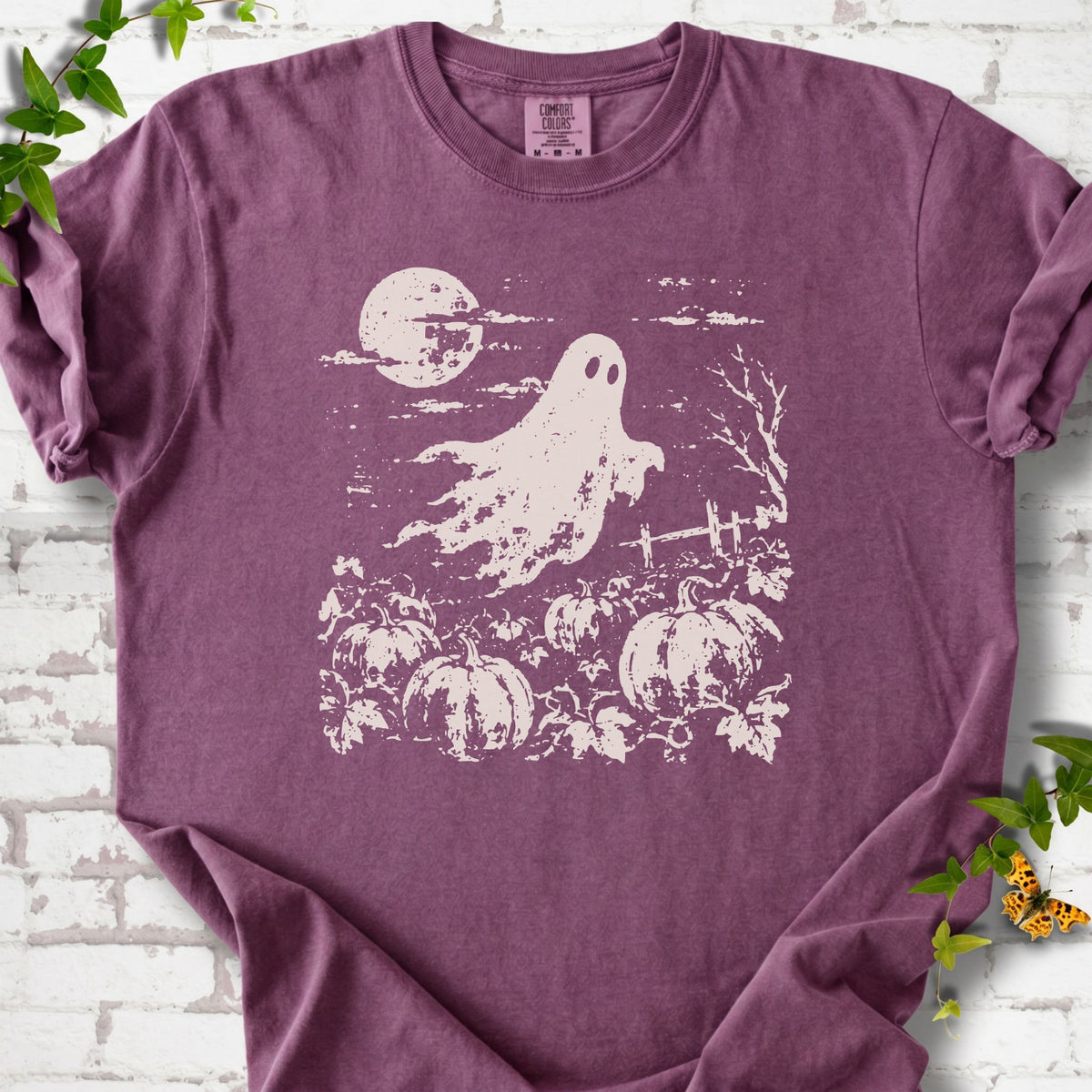Berry Comfort Colors® T-shirt flat lay featuring a distressed ghost floating above a pumpkin patch beneath a full moon.