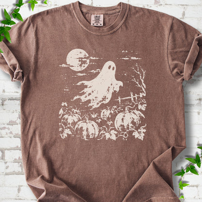 Espresso Comfort Colors® T-shirt flat lay featuring a distressed ghost floating above a pumpkin patch beneath a full moon.