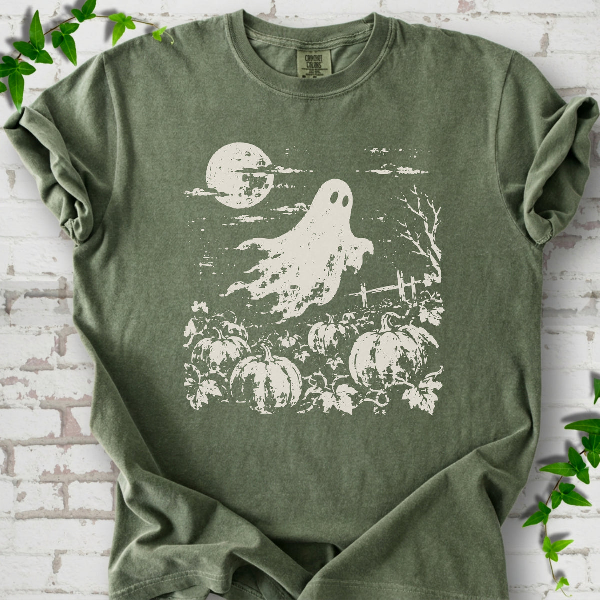 Moss Comfort Colors® T-shirt flat lay featuring a distressed ghost floating above a pumpkin patch beneath a full moon.