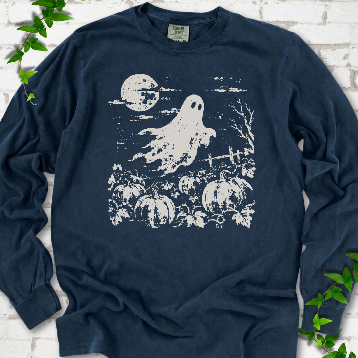 Midnight Comfort Colors® long sleeve tee flat lay featuring a distressed ghost floating above a pumpkin patch beneath a full moon.