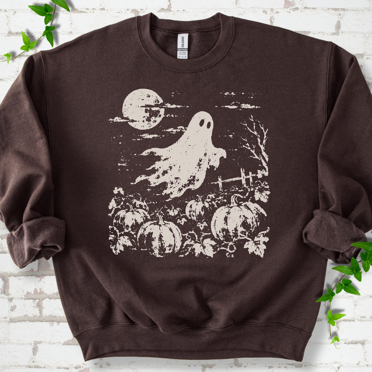 Dark Chocolate crewneck sweatshirt flat lay featuring a distressed ghost floating above a pumpkin patch beneath a full moon.