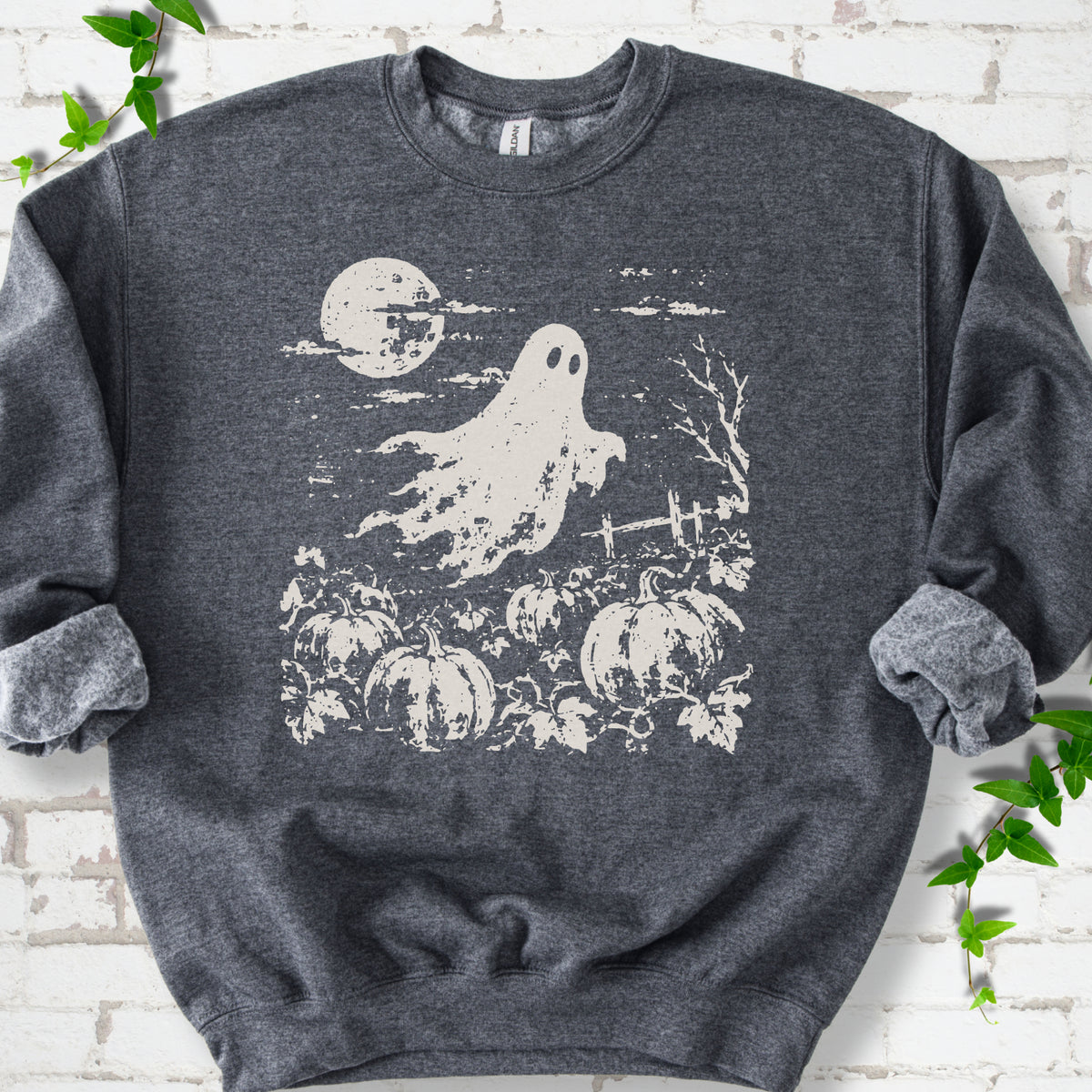 Dark Heather crewneck sweatshirt flat lay featuring a distressed ghost floating above a pumpkin patch beneath a full moon.