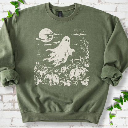 Military Green crewneck sweatshirt flat lay featuring a distressed ghost floating above a pumpkin patch beneath a full moon.