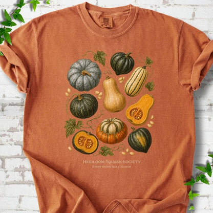 Yam Comfort Colors® short sleeve T-shirt flat lay featuring an illustrated collection of heirloom squash, pumpkins, seeds and vines with text "Heirloom Squash Society" and "Every shape has a season"