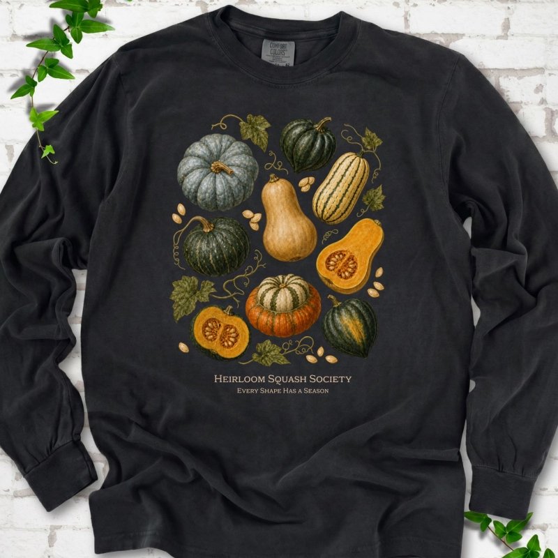 Black Comfort Colors® long sleeve T-shirt flat lay featuring an illustrated collection of heirloom squash, pumpkins, seeds and vines with text "Heirloom Squash Society" and "Every shape has a season"