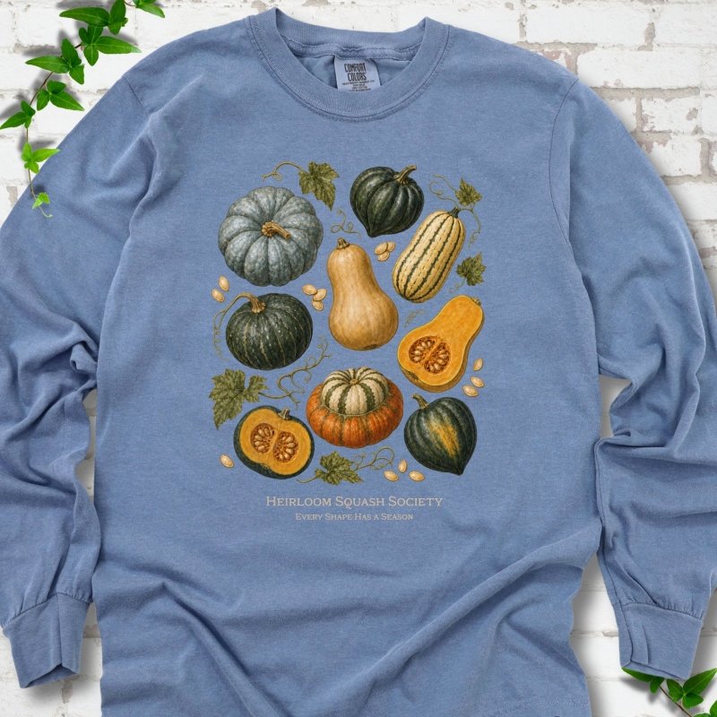 Blue Jean Comfort Colors® long sleeve T-shirt flat lay featuring an illustrated collection of heirloom squash, pumpkins, seeds and vines with text "Heirloom Squash Society" and "Every shape has a season"