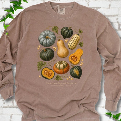 Espresso Comfort Colors® long sleeve T-shirt flat lay featuring an illustrated collection of heirloom squash, pumpkins, seeds and vines with text "Heirloom Squash Society" and "Every shape has a season"