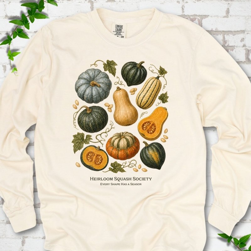Ivory Comfort Colors® long sleeve T-shirt flat lay featuring an illustrated collection of heirloom squash, pumpkins, seeds and vines with text "Heirloom Squash Society" and "Every shape has a season"