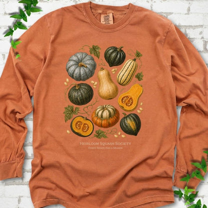 Yam Comfort Colors® long sleeve T-shirt flat lay featuring an illustrated collection of heirloom squash, pumpkins, seeds and vines with text "Heirloom Squash Society" and "Every shape has a season"