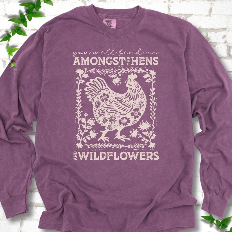 Berry Comfort Colors® long sleeve T-shirt flat lay featuring a cream hen and wildflower graphic with the words You Will Find Me Amongst the Hens and Wildflowers.