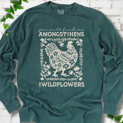Blue Spruce Comfort Colors® long sleeve T-shirt flat lay featuring a cream hen and wildflower graphic with the words You Will Find Me Amongst the Hens and Wildflowers.