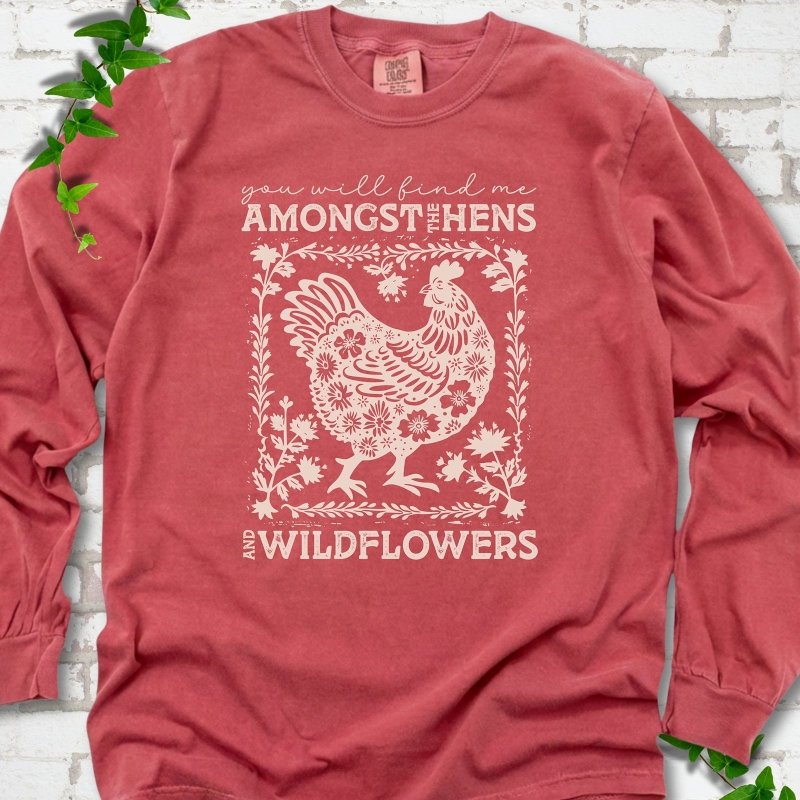 Crimson Comfort Colors® long sleeve T-shirt flat lay featuring a cream hen and wildflower graphic with the words You Will Find Me Amongst the Hens and Wildflowers.