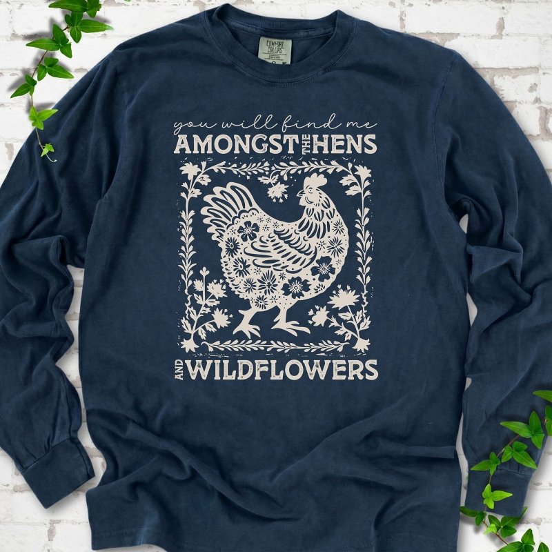 Midnight Comfort Colors® long sleeve T-shirt flat lay featuring a cream hen and wildflower graphic with the words You Will Find Me Amongst the Hens and Wildflowers.