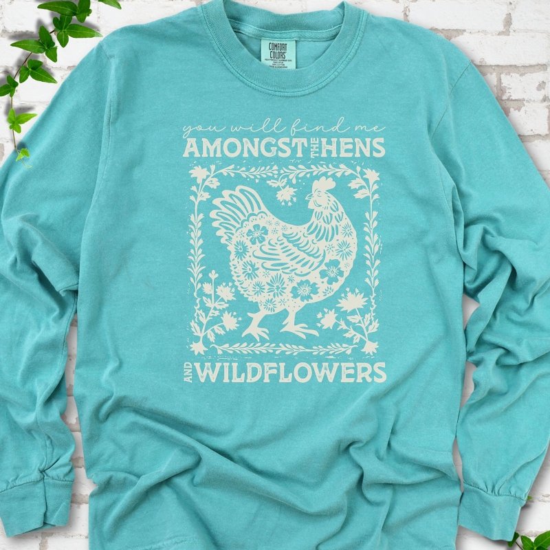 Seafoam Comfort Colors® long sleeve T-shirt flat lay featuring a cream hen and wildflower graphic with the words You Will Find Me Amongst the Hens and Wildflowers.