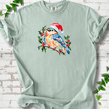 Bay T-shirt laid flat, featuring a colorful songbird in a red festive hat perched among holly leaves and berries.