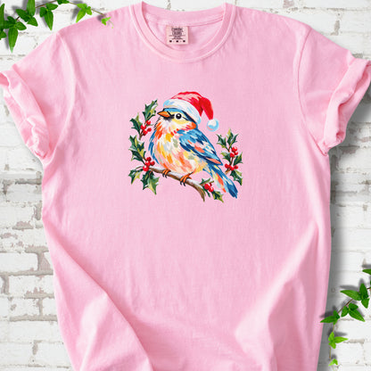 Blossom T-shirt laid flat, featuring a colorful songbird in a red festive hat perched among holly leaves and berries.