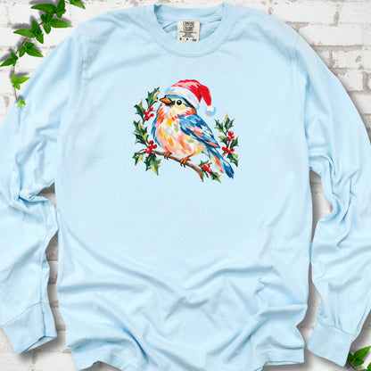 Chambray long sleeve T-shirt laid flat, featuring a colorful songbird in a red festive hat perched among holly leaves and berries.