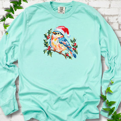 Island Reef long sleeve T-shirt laid flat, featuring a colorful songbird in a red festive hat perched among holly leaves and berries.