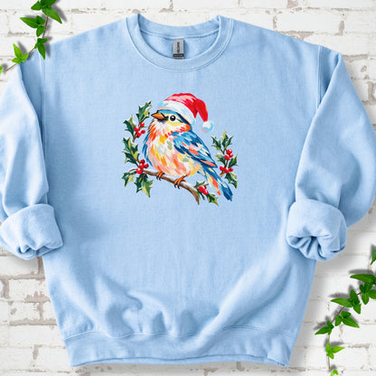 Light Blue classic sweatshirt laid flat, featuring a colorful songbird in a red festive hat perched among holly leaves and berries.