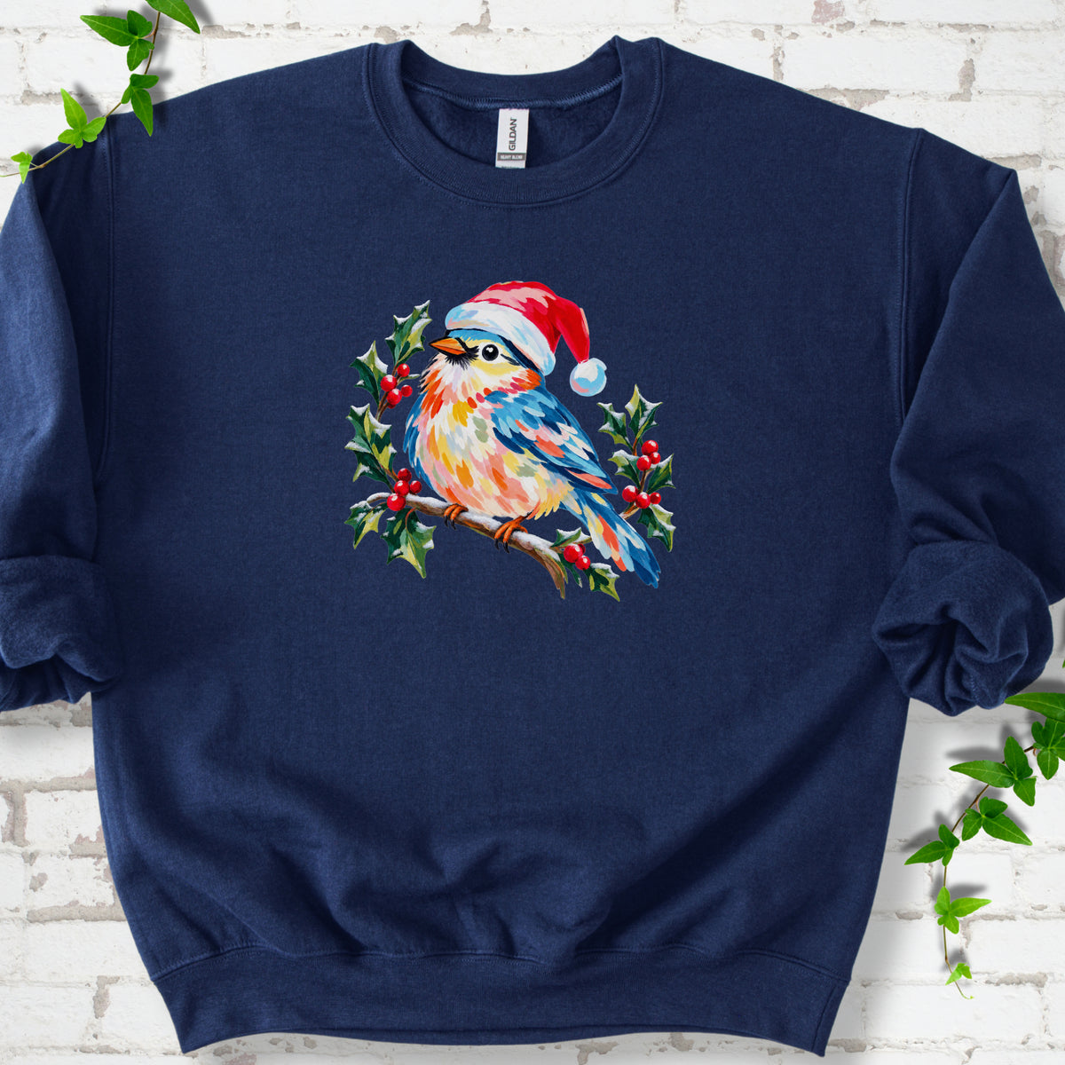 Navy classic sweatshirt laid flat, featuring a colorful songbird in a red festive hat perched among holly leaves and berries.