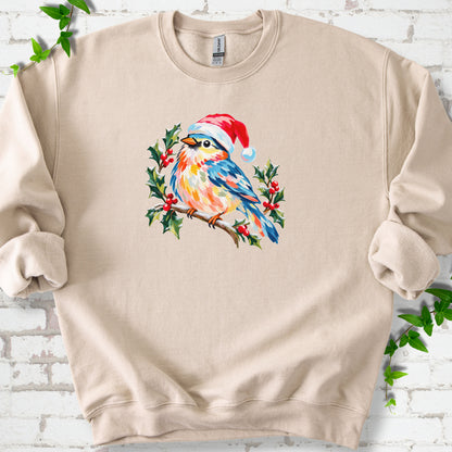 Sand classic sweatshirt laid flat, featuring a colorful songbird in a red festive hat perched among holly leaves and berries.