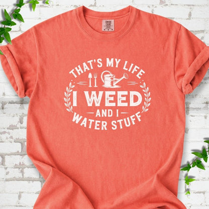 Bright Salmon Comfort Colors® T-shirt flat lay featuring That's My Life I Weed and I Water Stuff text with a watering can and garden tools.