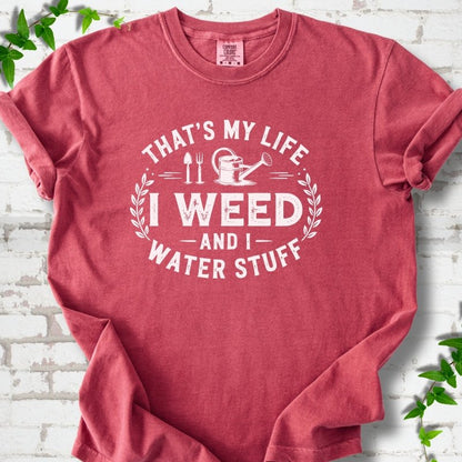 Crimson Comfort Colors® T-shirt flat lay featuring That's My Life I Weed and I Water Stuff text with a watering can and garden tools.