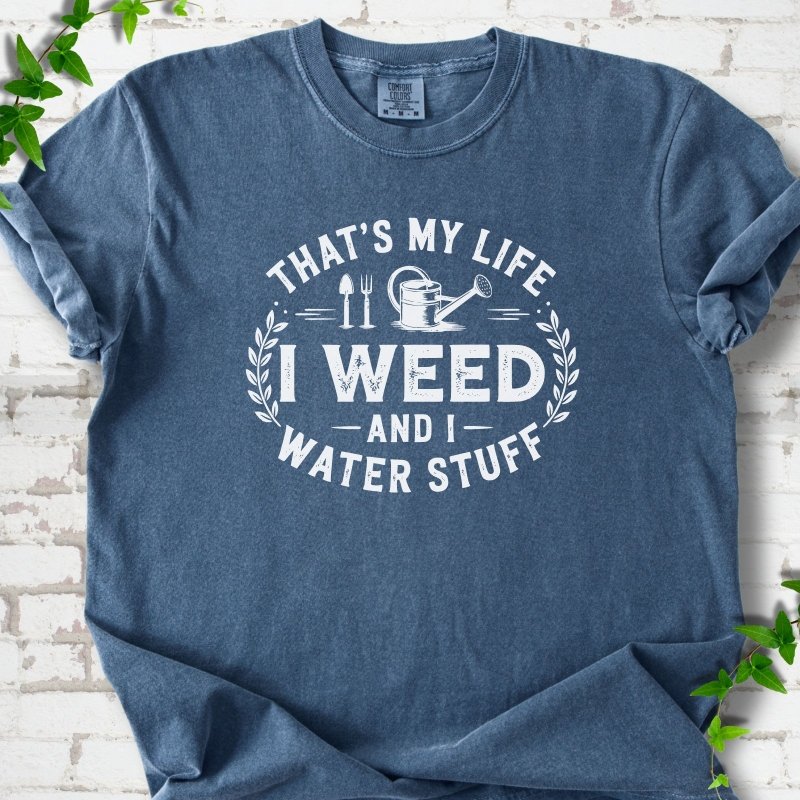 Denim Comfort Colors® T-shirt flat lay featuring That's My Life I Weed and I Water Stuff text with a watering can and garden tools.