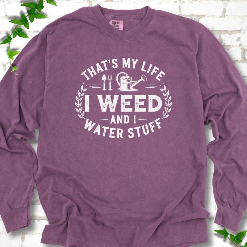 Berry Comfort Colors® long sleeve T-shirt flat lay featuring That's My Life I Weed and I Water Stuff text with a watering can and garden tools.