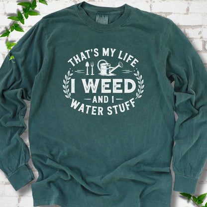 Blue Spruce Comfort Colors® long sleeve T-shirt flat lay featuring That's My Life I Weed and I Water Stuff text with a watering can and garden tools.