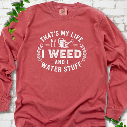 Crimson Comfort Colors® long sleeve T-shirt flat lay featuring That's My Life I Weed and I Water Stuff text with a watering can and garden tools.